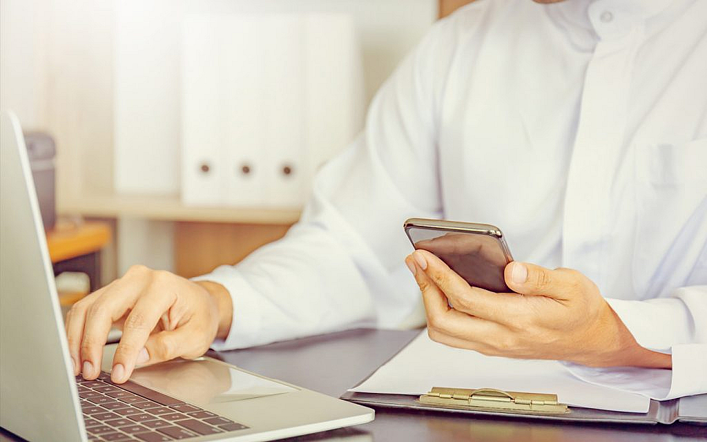 شخص يستخدم الهاتف والحاسوب