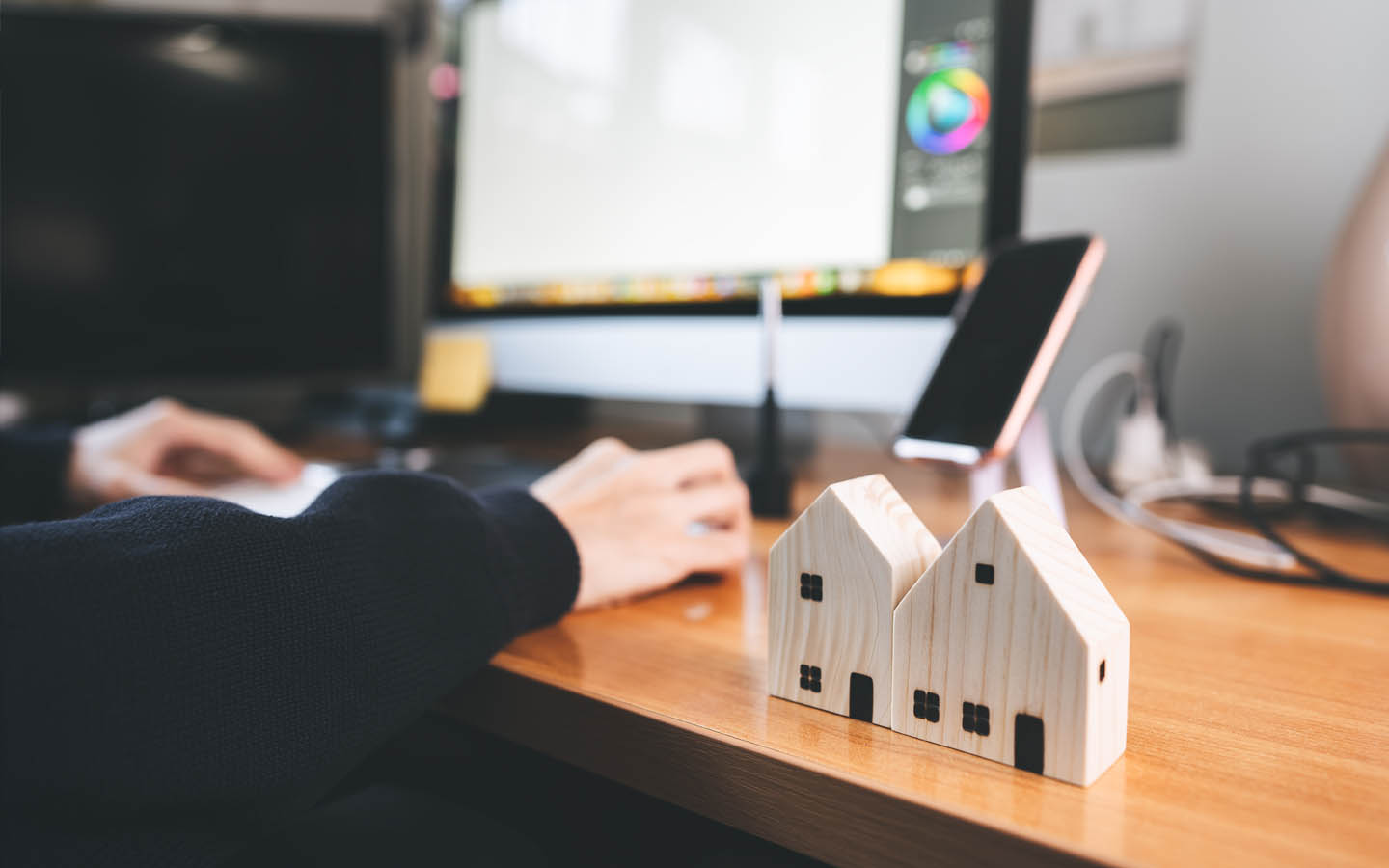 بيت خشبي صغير على مكتب وشخص يعمل