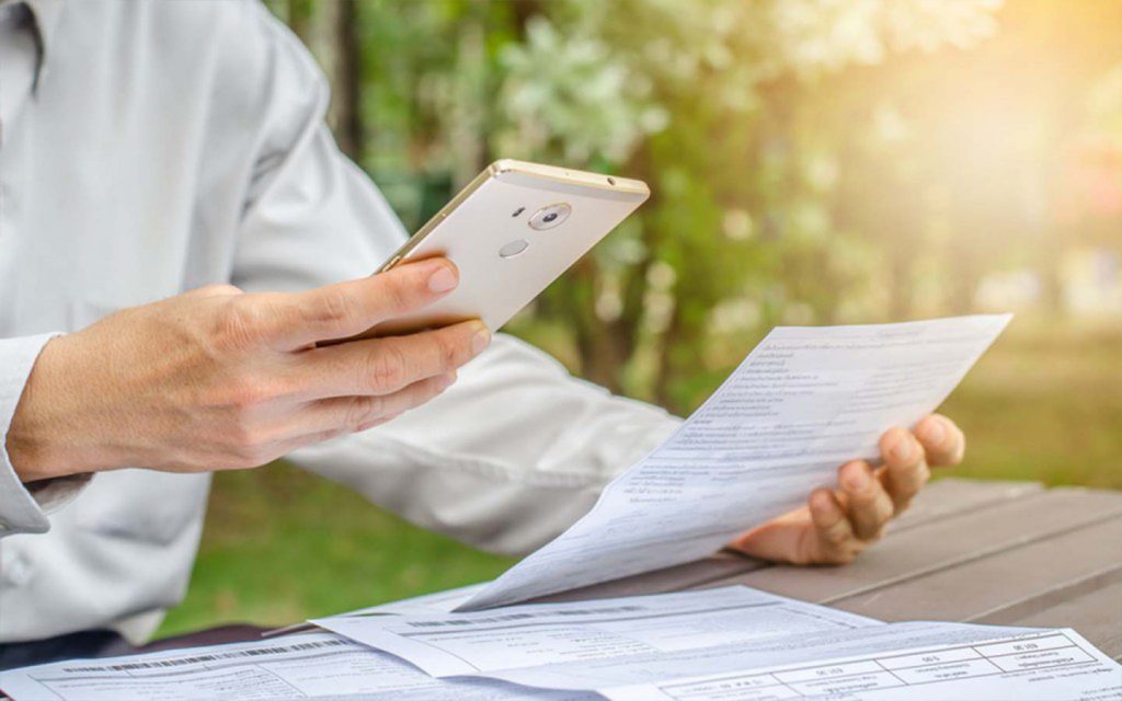 شخص يحمل الهاتف وورقة بيده