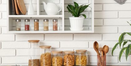 Organized kitchen counter and wall shelf featuring glass storage jars with pasta and grains