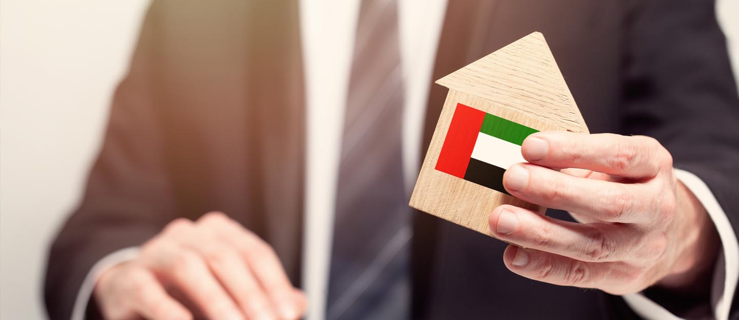 رجل يحمل مجسم منزل عليه علم الامارات