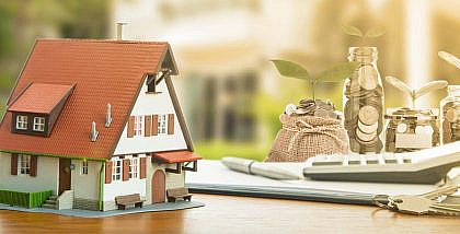 مجسم منزل وعملات معدنية ومفتاح وآلة حاسبة