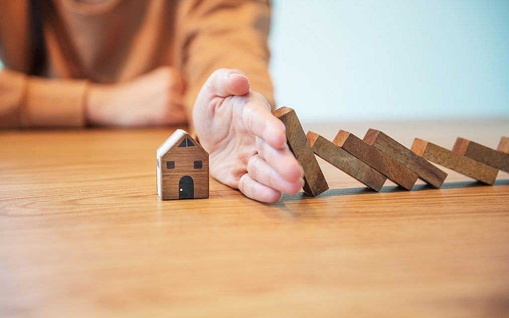 يد تفص بين مجسم منزل وقطع خشبية 