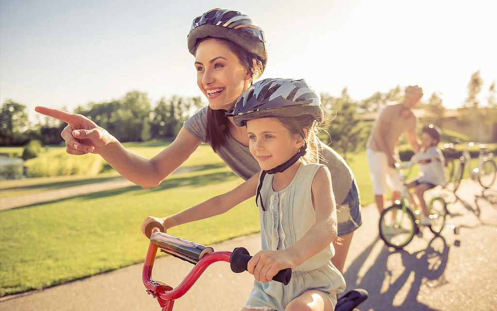 أم مع طفلتها التي تركب دراجة هوائية 