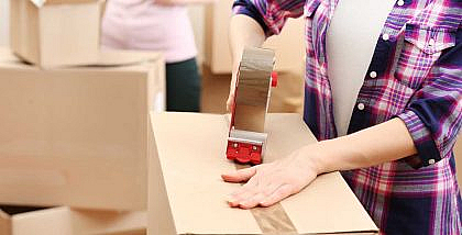 شخص يقوم بإغلاق صندوق كرتوني بواسطة اللاصق