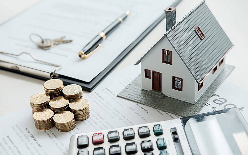 قطع نقدية بجانب مجسم لمنزل