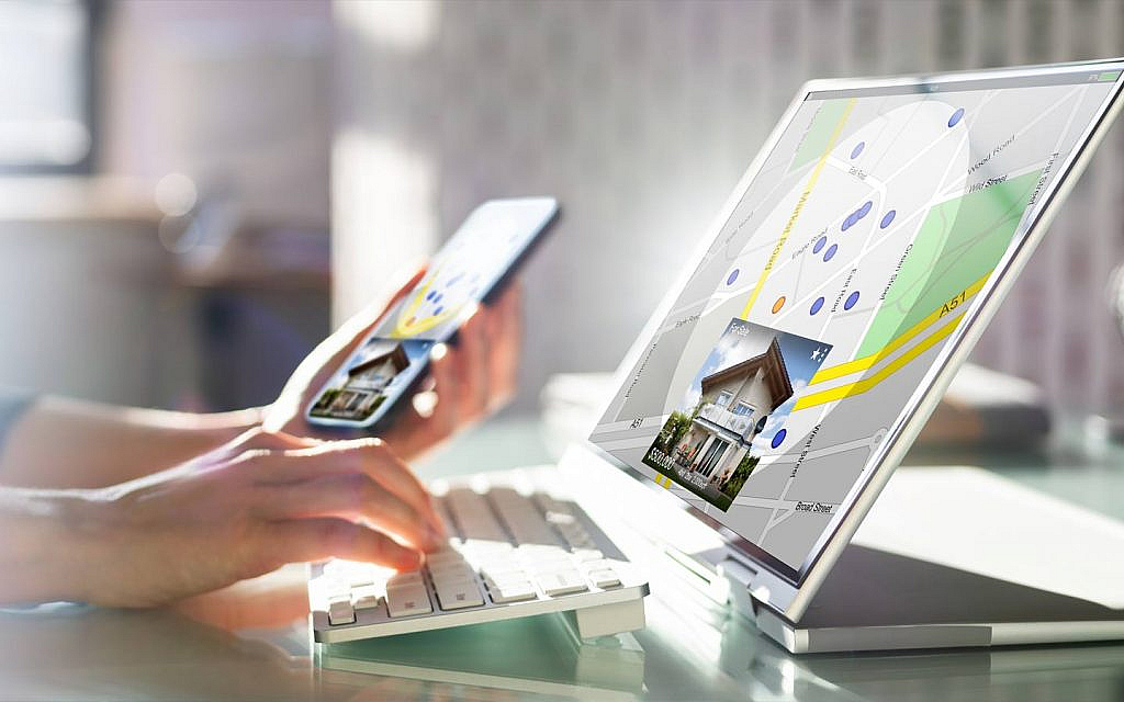 شخص يستخدم الهاتف والحاسوب للبحث عن منزل