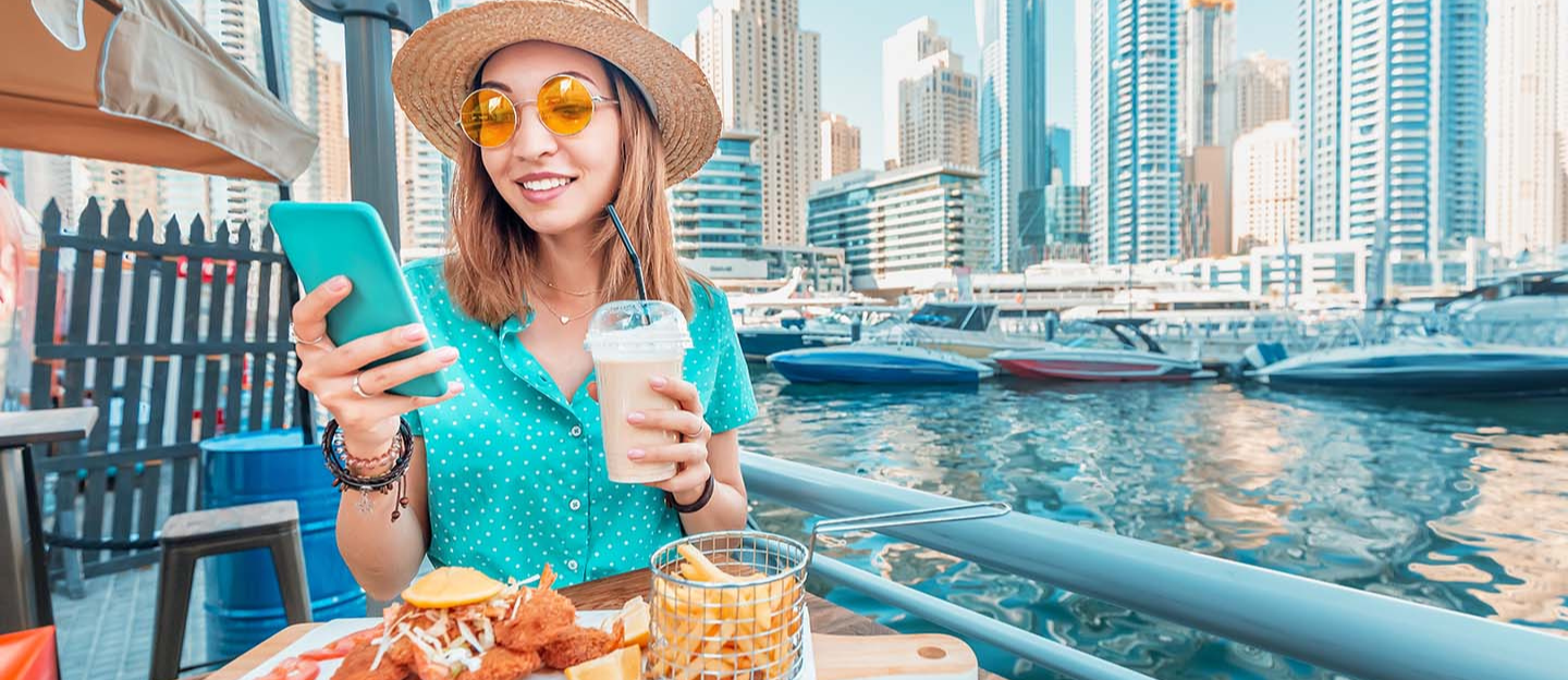 فتاة تستخدم الهاتف أثناء جلوسها في إحدى مطاعم منطقة دبي مارينا