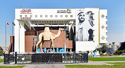 مبنى بلدية دبي مع تمثال لجمل وصورة للشيخ زايد بن سلطان