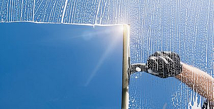 شخص ينطف زجاج نافذة بمساحة زجاج