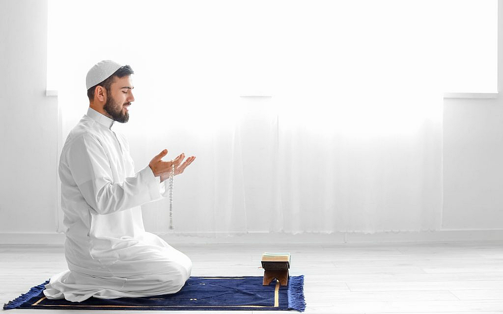 شخص يدعي على سجادة صلاة