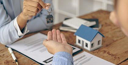 بائع يسلم مفتاح منزل لمشتري بعد توقيع الاتفاقيات