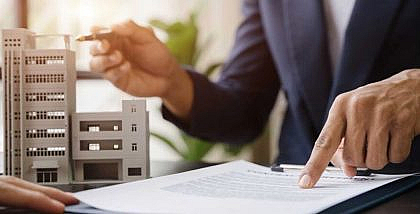 شخص يشرح عقد ويؤشر على مجسم مبنى