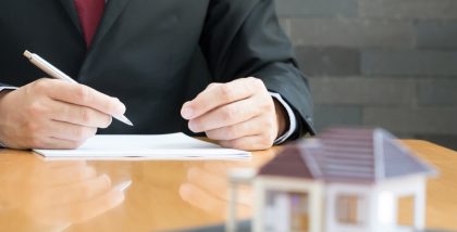 مجسم منزل وشخص يوقع أوراق