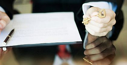 شخص يمسك أوراق ومفتاح منزل