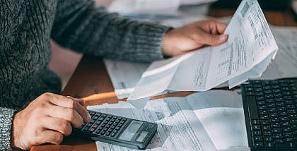 شخص يمسك بورقة ويستخدم الآلة الحاسبة