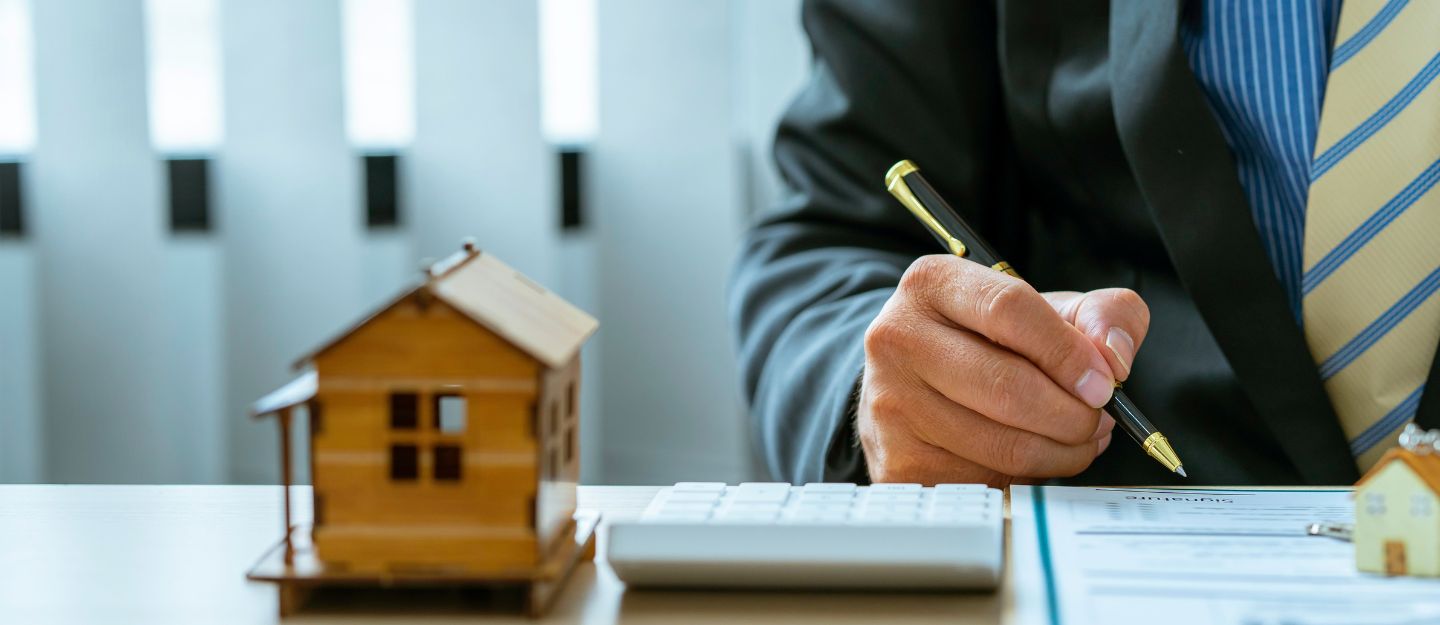 businessman in a suit signing paperwork at a desk