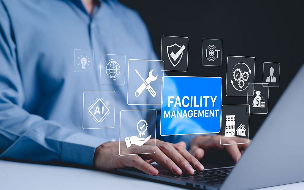 Person interacting with a laptop displaying 'Facility Management' and related icons like AI, IoT and security.

