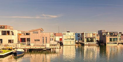 A row of modern floating villas on a calm body of water under a clear sky