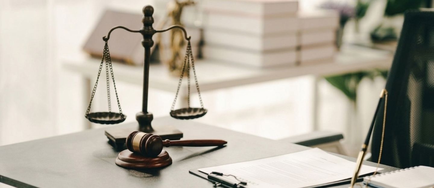 A scale of justice and wooden gavel on a desk.