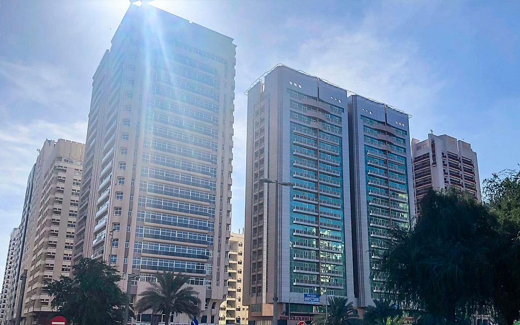 Tall residential and commercial buildings line Electra Street under a bright sky.