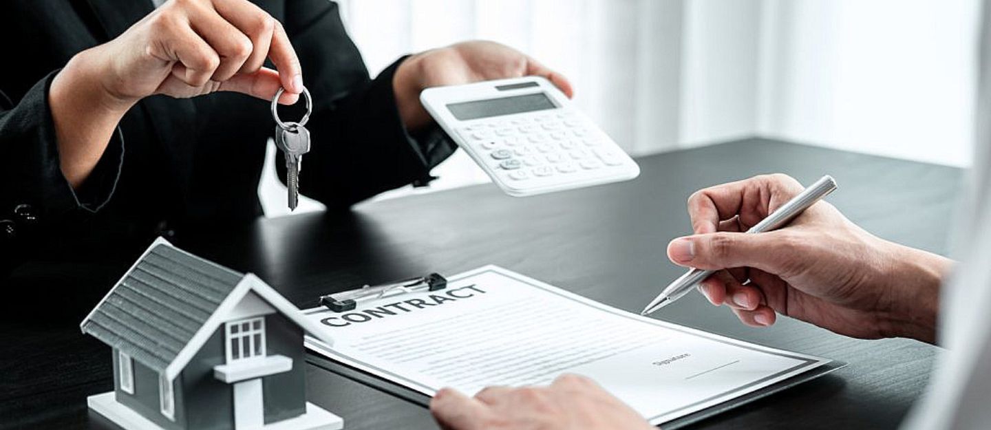 A landlord offering keys and a calculator to a tenant signing a contract, following tenant screening questions.