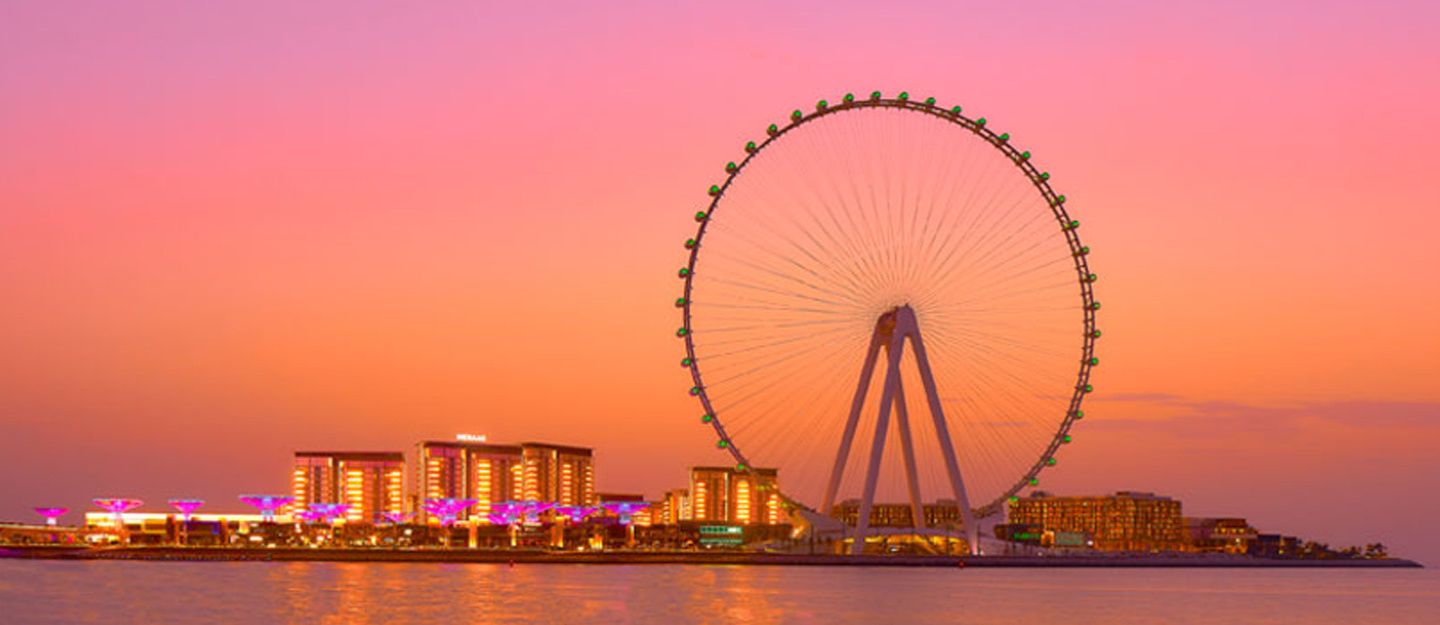 Ain Dubai Ferris wheel and illuminated buildings at sunset, visible from Areas to Rent Villas With Ain Dubai View.