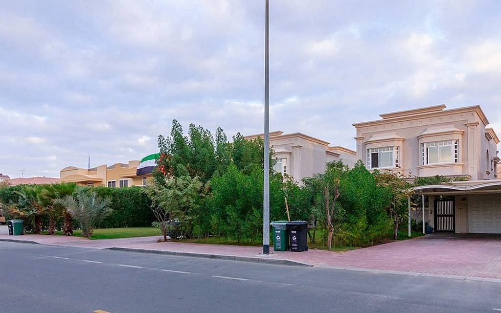 Street view of residential villas with green landscaping, in Umm Suqeim.