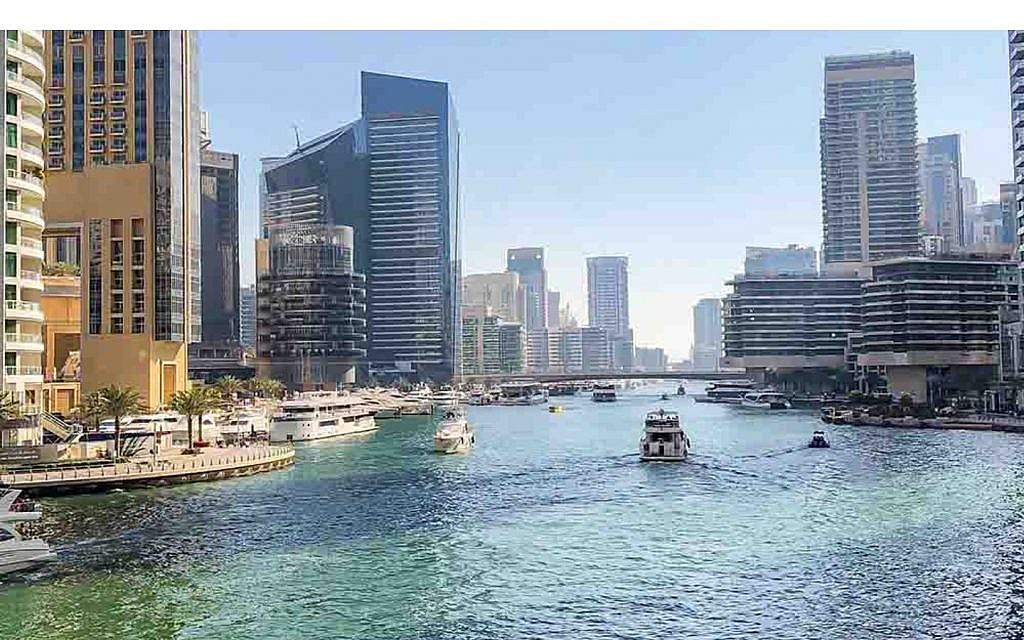 Panoramic view of Dubai Marina, with boats on the water and modern skyscrapers lining the waterfront.