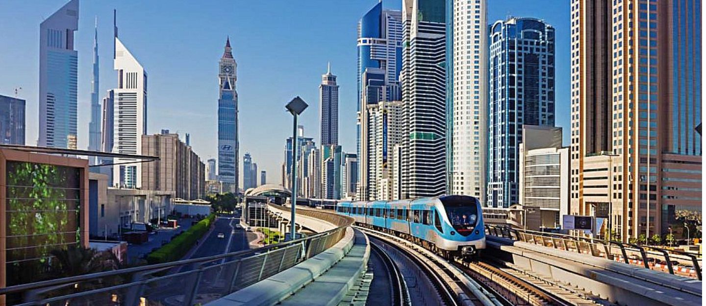 Dubai Metro train on an elevated track amidst skyscrapers, illustrating living near a metro station.