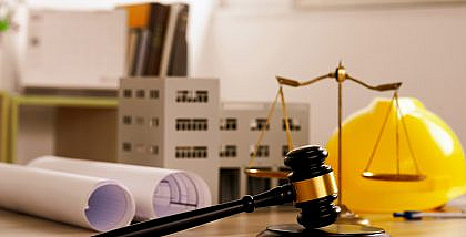 مجسم مبنى سكني وخوذة عامل ومطرقة قاضي