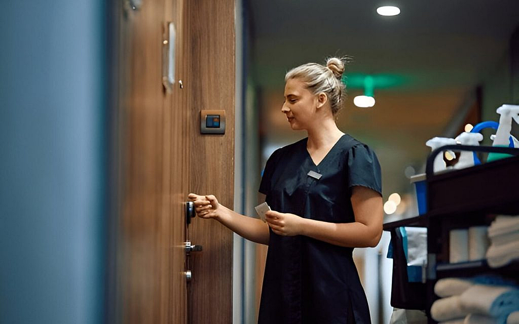A cleaner knocking at the door of a branded apartment