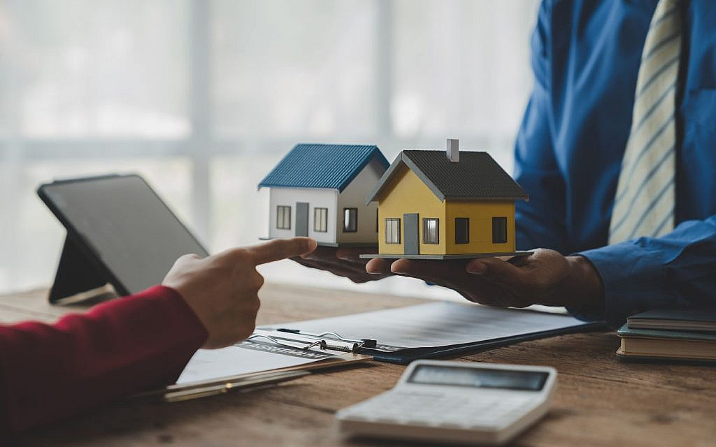 مجسمات منازل صغير وآلة حاسبة وأوراق