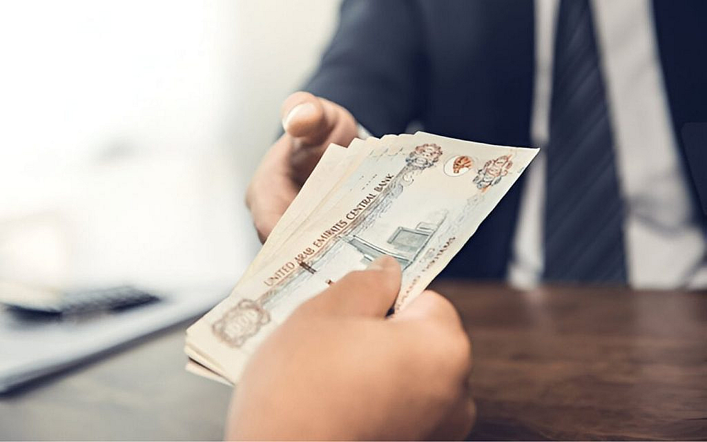 شخص يحمل نقود بالدرهم الإماراتي