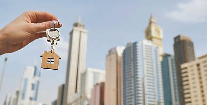 شخص يحمل مفتاح مع مجسم منزل