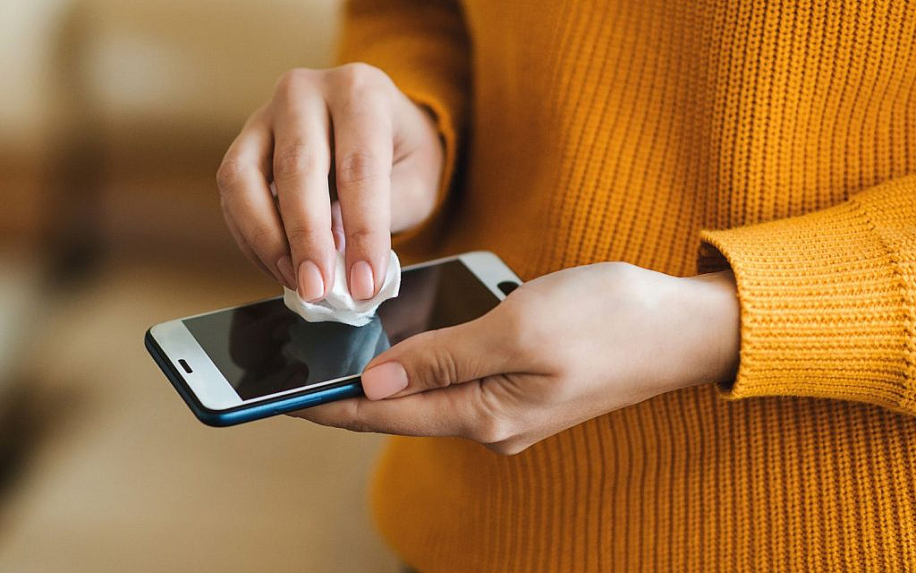 سيدة تقوم بتنظيف شاشة هاتف ذكي