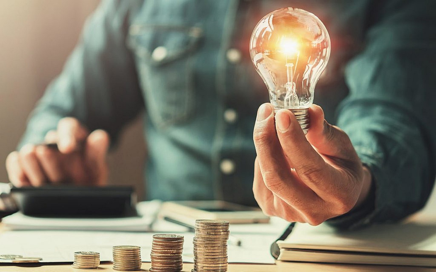 عملات نقدية وشخص يمسك لمبة