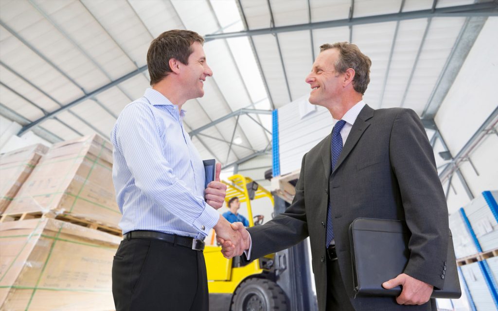 شخصان يصافحان بعضهما في أحد المستودعات