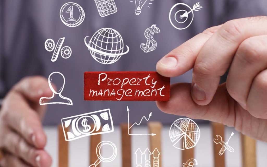 A person holding a red block labeled "Property Management" surrounded by illustrated business icons like a globe, dollar signs and graphs.