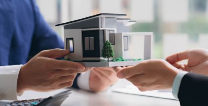 أشخاص يحملون مجسم منزل