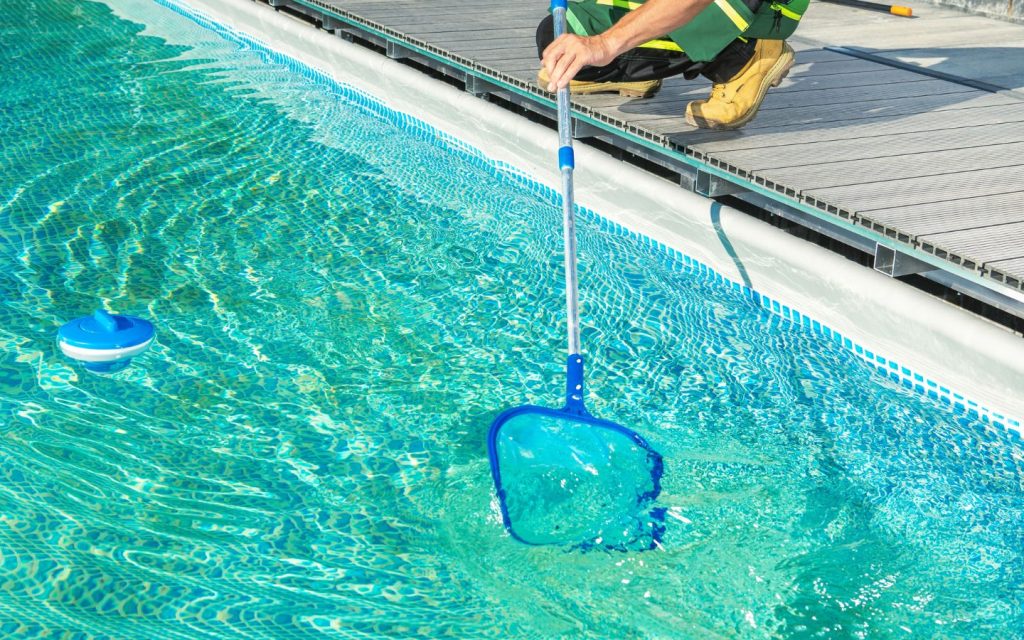 Professional pool cleaners in RAK taking debris out of water 
